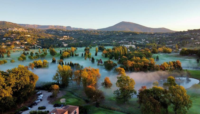 Vue aérienne du parcours du Golf de la Grande Bastide en automne, avec une légère brume recouvrant les fairways.