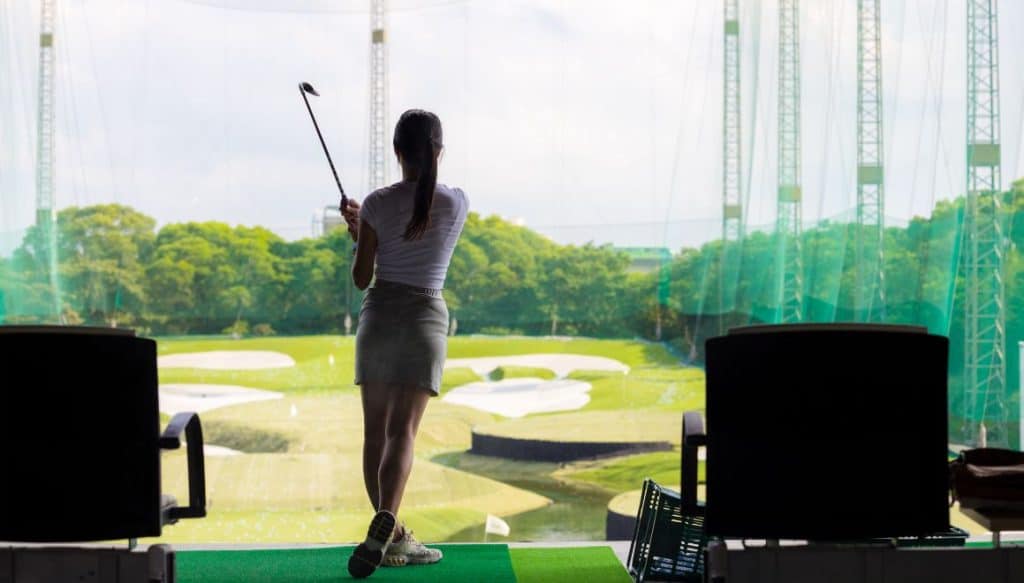 Joueuse de golf frappant une balle au practice en travaillant la variation des trajectoires.