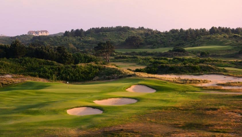 Parcours de golf sur la Côte d’Opale avec dunes et mer en arrière-plan.